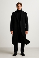 Um homem está de pé, de frente, contra um fundo liso e claro. Ele veste um Casaco Zellum Sobretudo Masculino Longo Abaixo dos Joelhos com blusa de gola alta preta, calças pretas e sapatos sociais. Seu cabelo está bem penteado e seus braços estão relaxados ao lado do corpo.