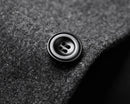 Close-up do botão preto no tecido cinza do casaco sobretudo masculino Zellum, evidenciando a textura e o acabamento de qualidade.