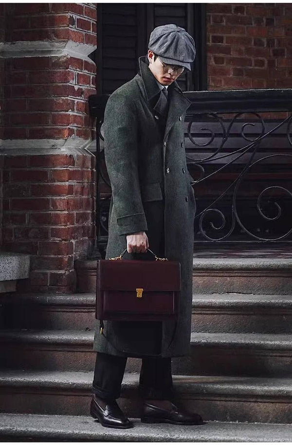 Homem com sobretudo longo verde escuro, boina cinza e pasta de couro, em look vintage sofisticado para o inverno