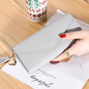 Mão segurando carteira de couro cinza com abeta de envelope e ornamento dourado