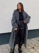Mulher usando sobretudo cinza longo com gola clássica, top preto e calça preta
