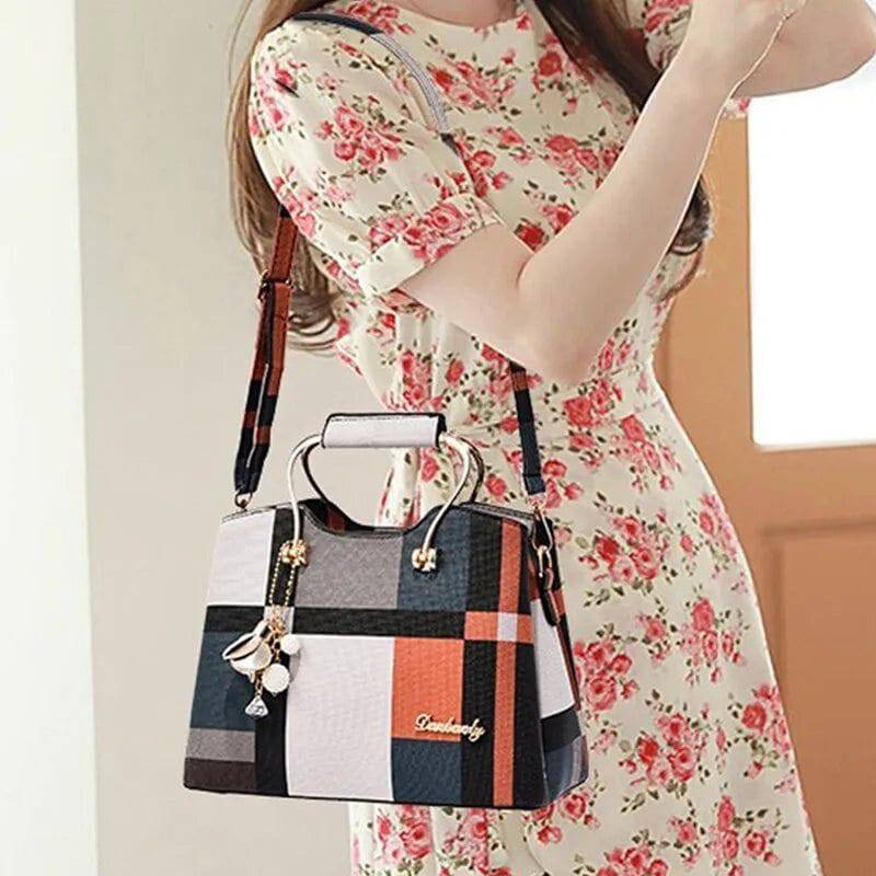 Alt text: Bolsa feminina de couro estruturada com estampa xadrez preta e branca.
