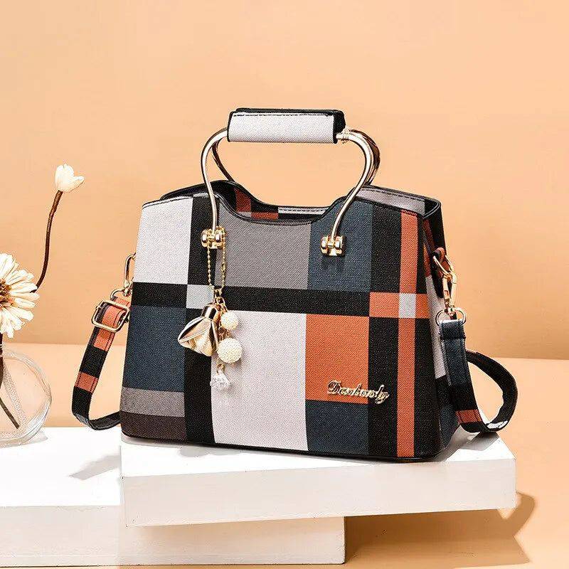 Alt text: Bolsa feminina de couro estruturada com estampa xadrez preta.
