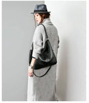Mulher de cardigan cinza claro com bolsa de couro preta no ombro