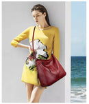 Mulher com vestido amarelo estampado segurando bolsa de couro vermelha