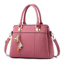 Bolsa tote rosa estruturada com padrão texturizado, alças duplas e alça transversal, com charm pássaro dourado.