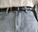 Cinto fino de couro com fivela dourada, vestido sobre calça jeans clara