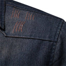 Detalhe do ombro de jaqueta jeans azul escuro com costuras visíveis e textura de tecido