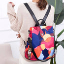 Mulher com mochila feminina estampa geométrica colorida, alças pretas e chaveiro de urso