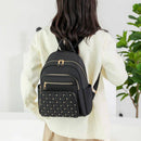 Mulher de costas com mochila preta de nylon com tachas no bolso frontal e detalhes dourados