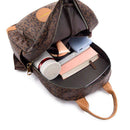 Mochila de couro marrom aberta mostrando interior com garrafa térmica, power bank e caderno