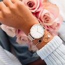 Relógio minimalista de aço inoxidável com mostrador branco na mão de mulher