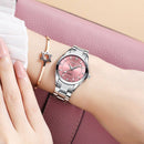 Relógio feminino com mostrador rosa e pulseira de aço inox, usado com pulseira de ouro rosé