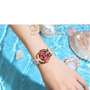 Relógio feminino rose-gold com mostrador vermelho e pulseira de aço no pulso