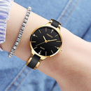 Relógio feminino dourado com mostrador preto e pulseira de couro, acompanhado de pulseira com strass