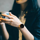 Relógio minimalista com mostrador preto e pulseira de aço dourado em pulso feminino