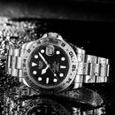 Relógio masculino de aço inox com mostrador preto e pulseira de metal.