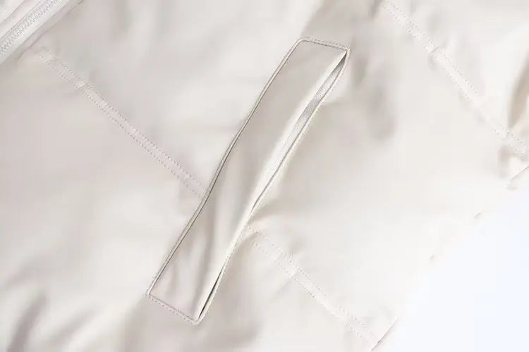 Close-up da Zellum Jaqueta Puffer Feminina para Inverno em bege claro, mostrando bolsos acolchoados e costurados e um tecido macio e suave - uma opção ideal e elegante para o inverno.