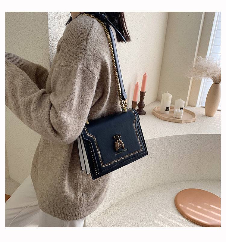 Alt text: Bolsa tiracolo feminina de couro estruturada preta elegante.