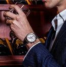 Homem usando relógio Zeppelin clássico com pulseira de couro e cronógrafo, ao segurar bebida