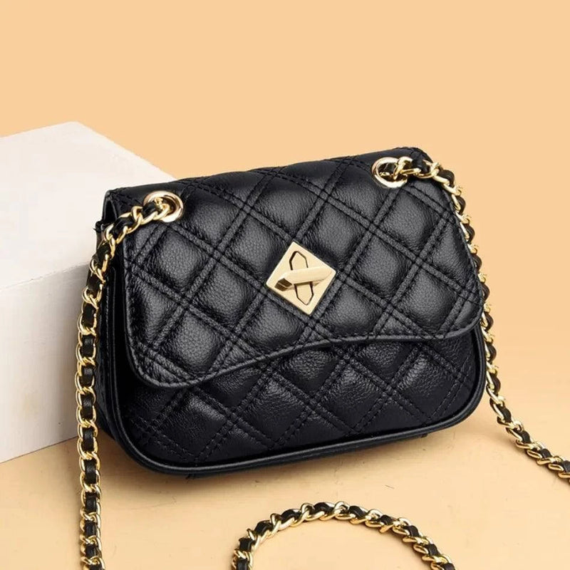 Alt text: Bolsa tiracolo acolchoada preta com corrente em couro sintético.