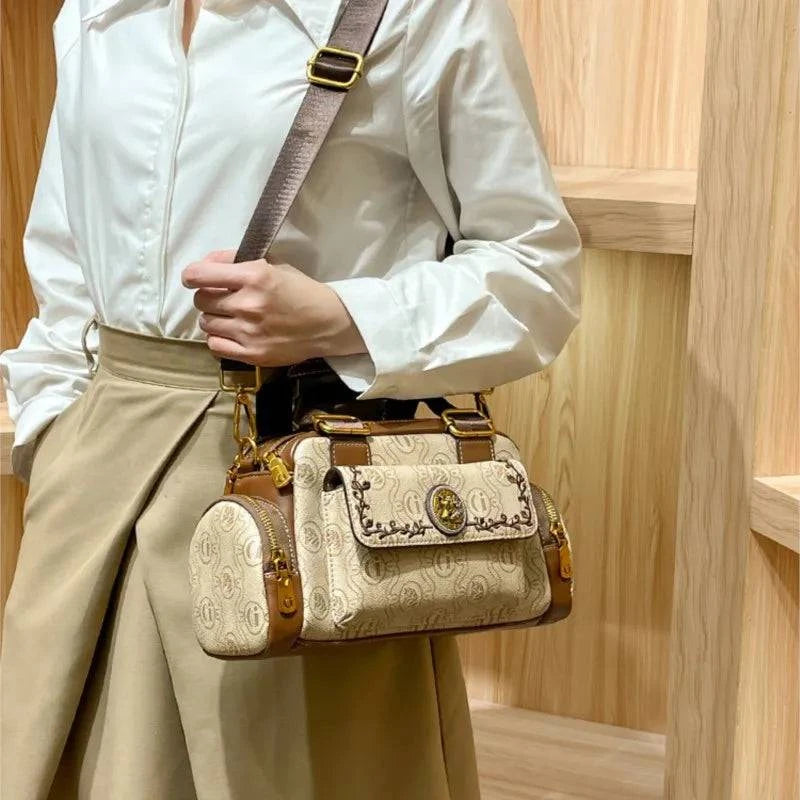 Alt text: Bolsa baú feminina preta em couro com alça ajustável.