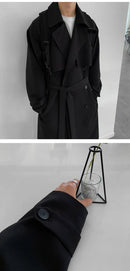 Trench coat preto até os joelhos com cinto e detalhe do botão no punho