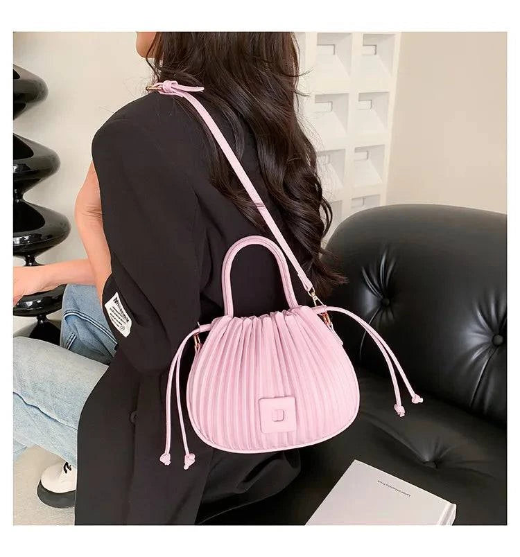 Alt text: Bolsa feminina bucket texturizada em tom neutro elegante.