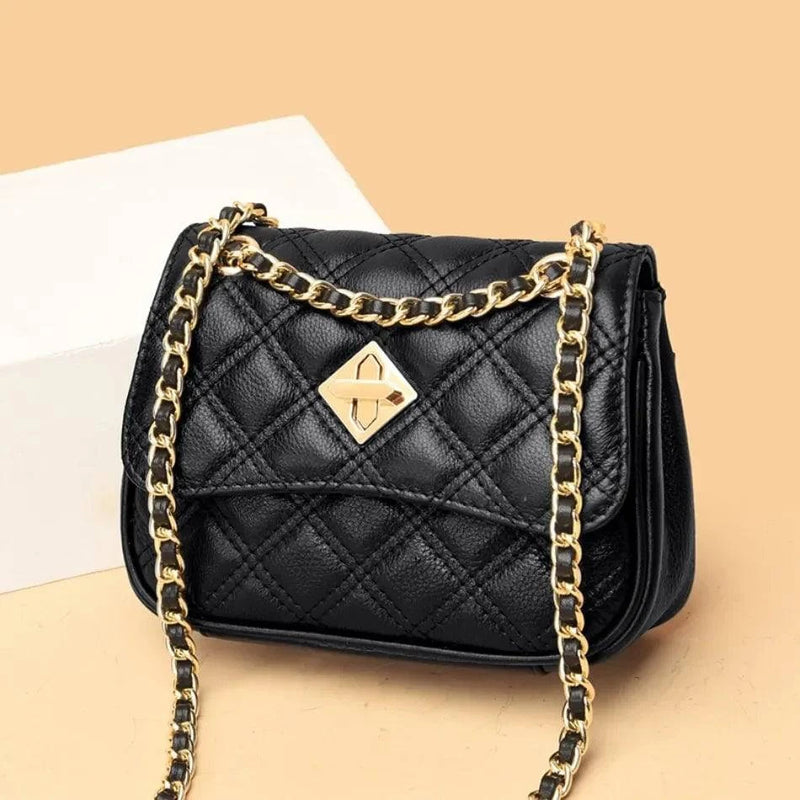 Alt text: Bolsa tiracolo acolchoada preta com corrente de metal.