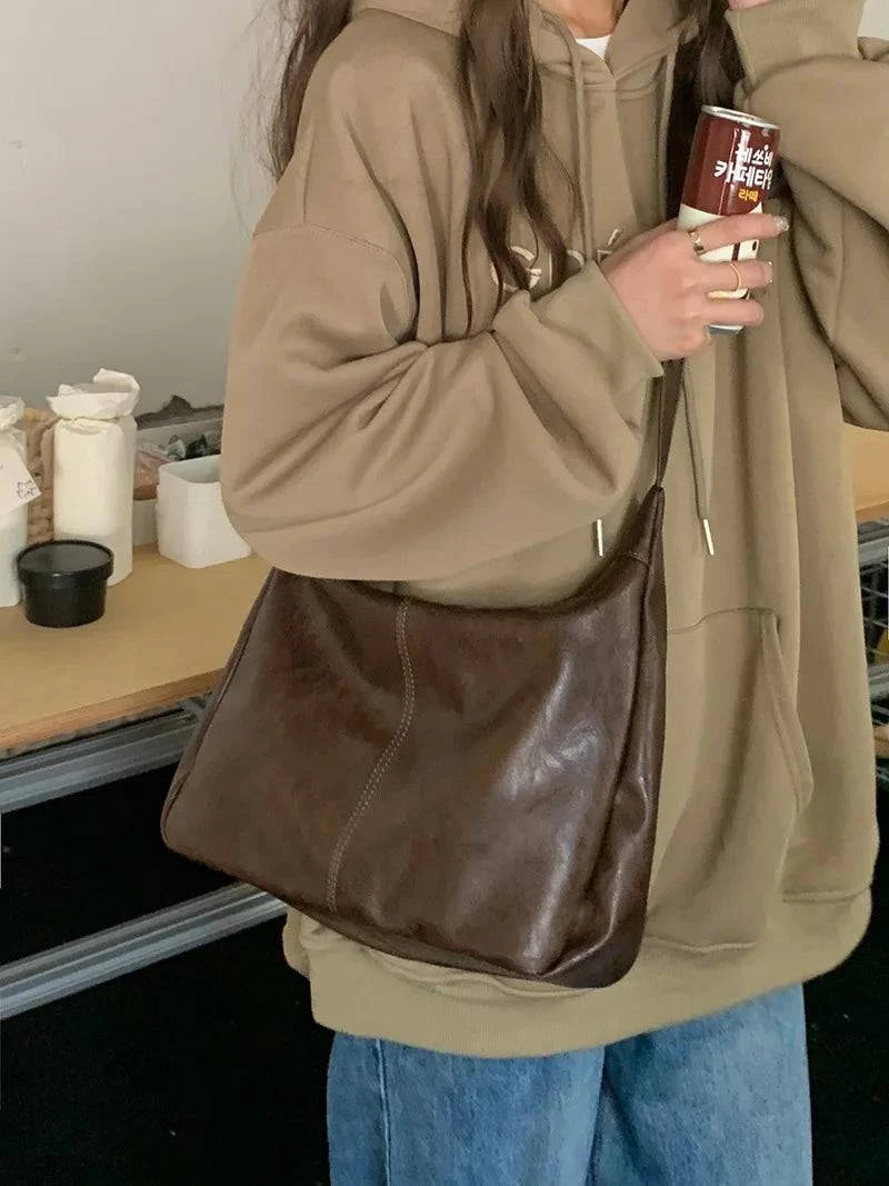 Alt text: Bolsa feminina de couro hobo marrom, elegante e espaçosa.
