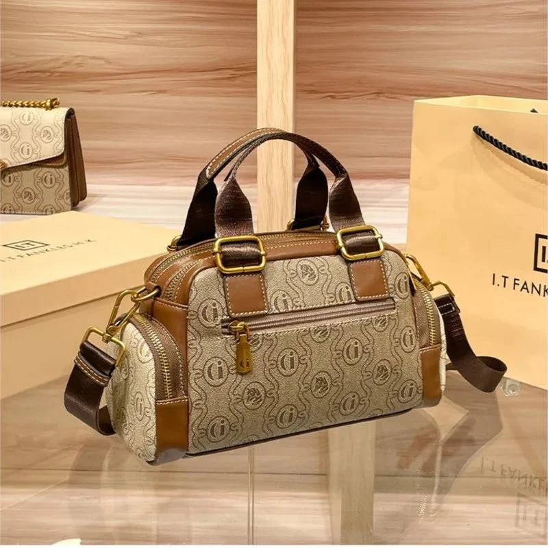 Alt text: Bolsa baú feminina preta em couro com alça transversal ajustável.