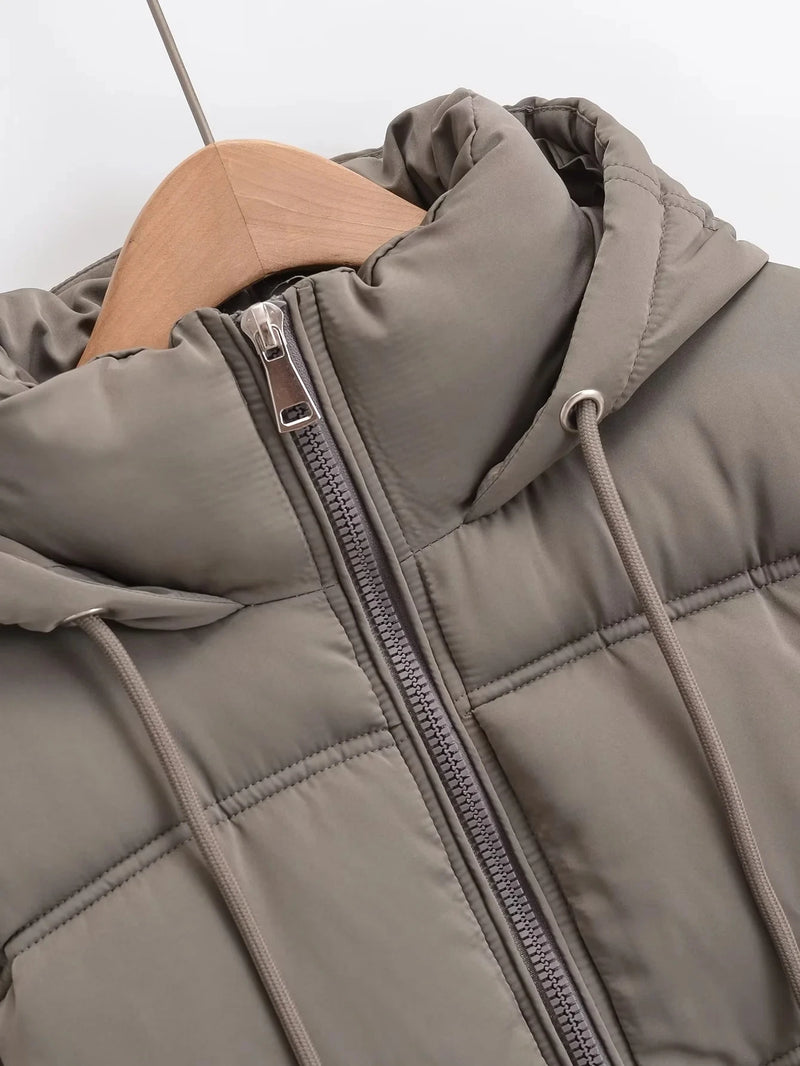 Um close-up da Jaqueta Feminina Puffer para Inverno da Zellum em um cabide de madeira, mostrando seu design acolchoado, zíper frontal, capuz com cordões e tecido liso contra um fundo branco.