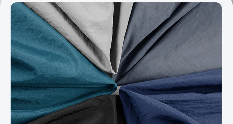 Um leque de amostras de tecido em azul, cinza, preto e branco destaca as texturas perfeitas para a criação da Zellum Jaqueta Corta-vento Esportiva Masculina.