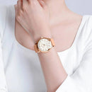 Relógio rosé com mostrador branco e pulseira de couro no pulso