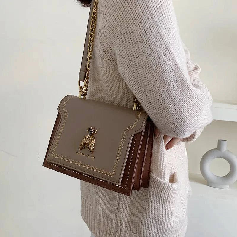 Alt text: Bolsa tiracolo feminina de couro estruturada na cor marrom.