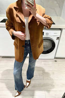 Mulher usando jaqueta de camurça caramelo com jeans azul e top branco