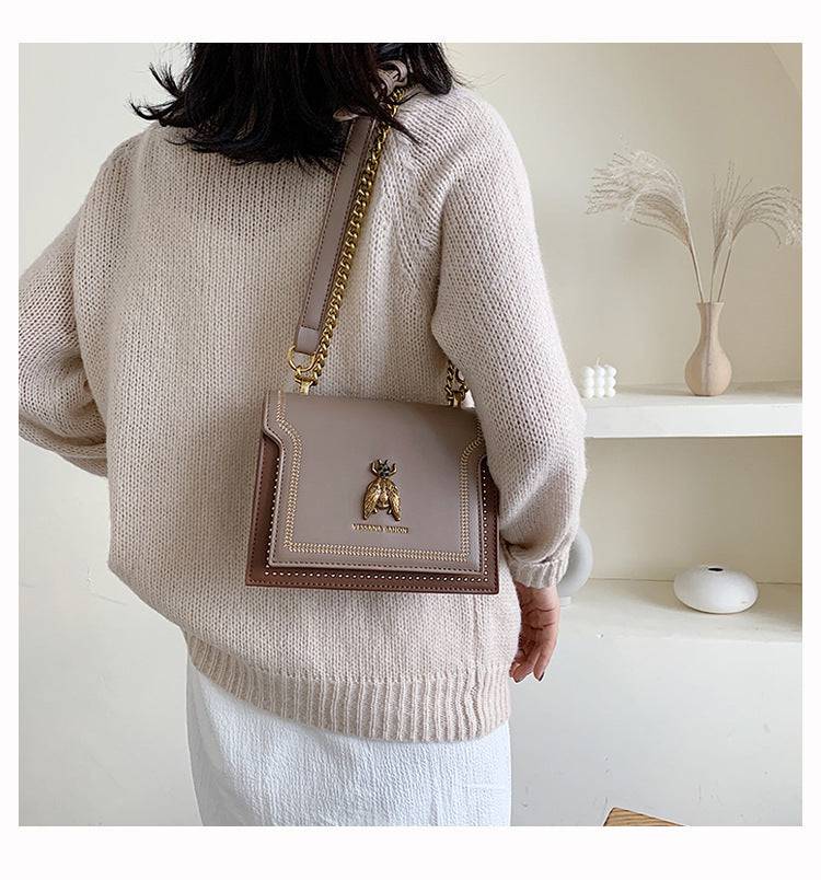 Alt text: Bolsa tiracolo feminina de couro estruturada preta elegante.