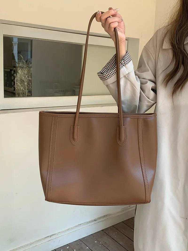 Alt text: Bolsa feminina de couro preto estilo Tote Glam elegante.