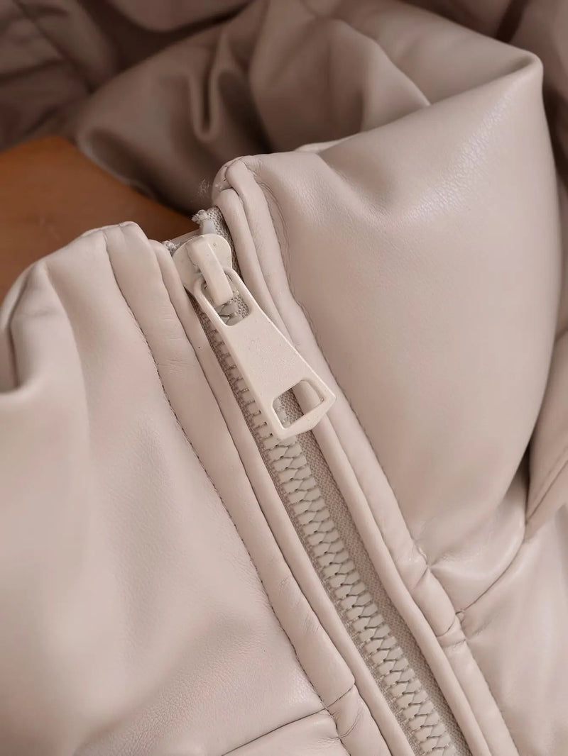 Close-up de um zíper de plástico bege e costura detalhada no tecido acolchoado, semelhante a couro, da Jaqueta Puffer Feminina para Inverno da Zellum, mostrando sua textura macia e felpuda, ideal para jaquetas de inverno.