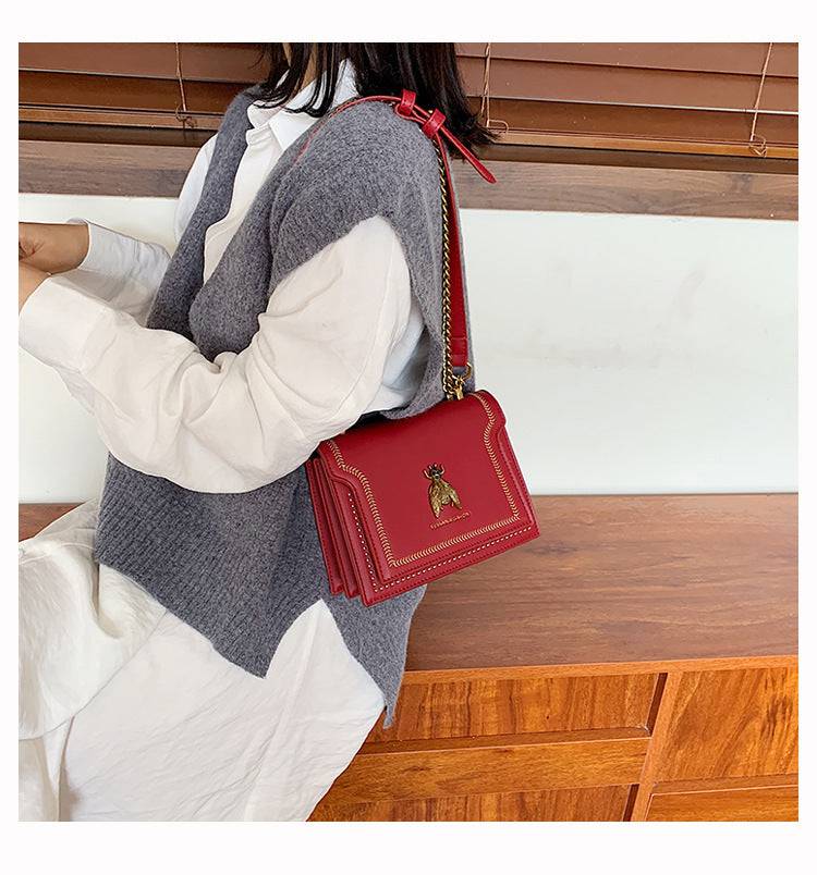 Alt text: Bolsa tiracolo feminina de couro estruturada na cor marrom.