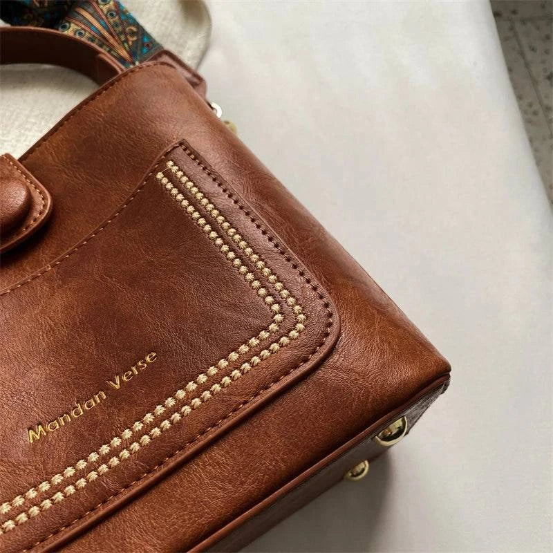 Alt text: Bolsa Tote Feminina Transversal Pequena Cristalle em couro marrom.