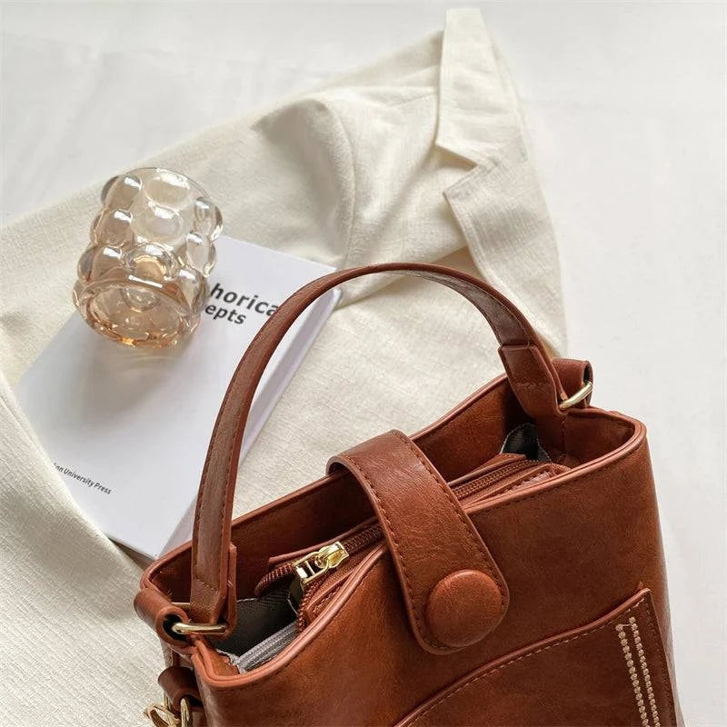 Alt text sugerido: Bolsa Tote feminina pequena em couro sintético preto.