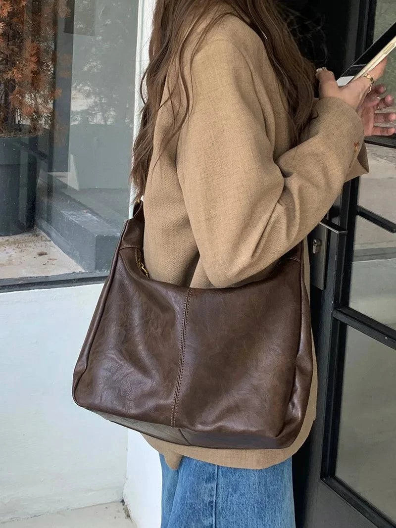 Alt text: Bolsa feminina de couro hobo marrom elegante e espaçosa.