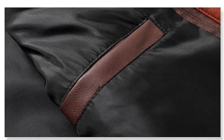 Close-up da Jaqueta de Couro Masculina com Capuz Zellum, mostrando o tecido preto com um bolso marrom com acabamento em couro. O material liso contrasta com o couro fosco, destacando a borda do bolso e parte do forro.