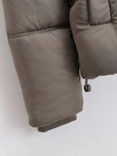 Detalhe de jaqueta puffer feminina taupe com costura acolchoada, punho elástico e cordão ajustável