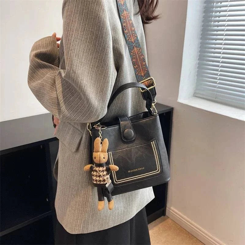 Alt text: Bolsa Tote Feminina Transversal Pequena Cristalle em couro preto.