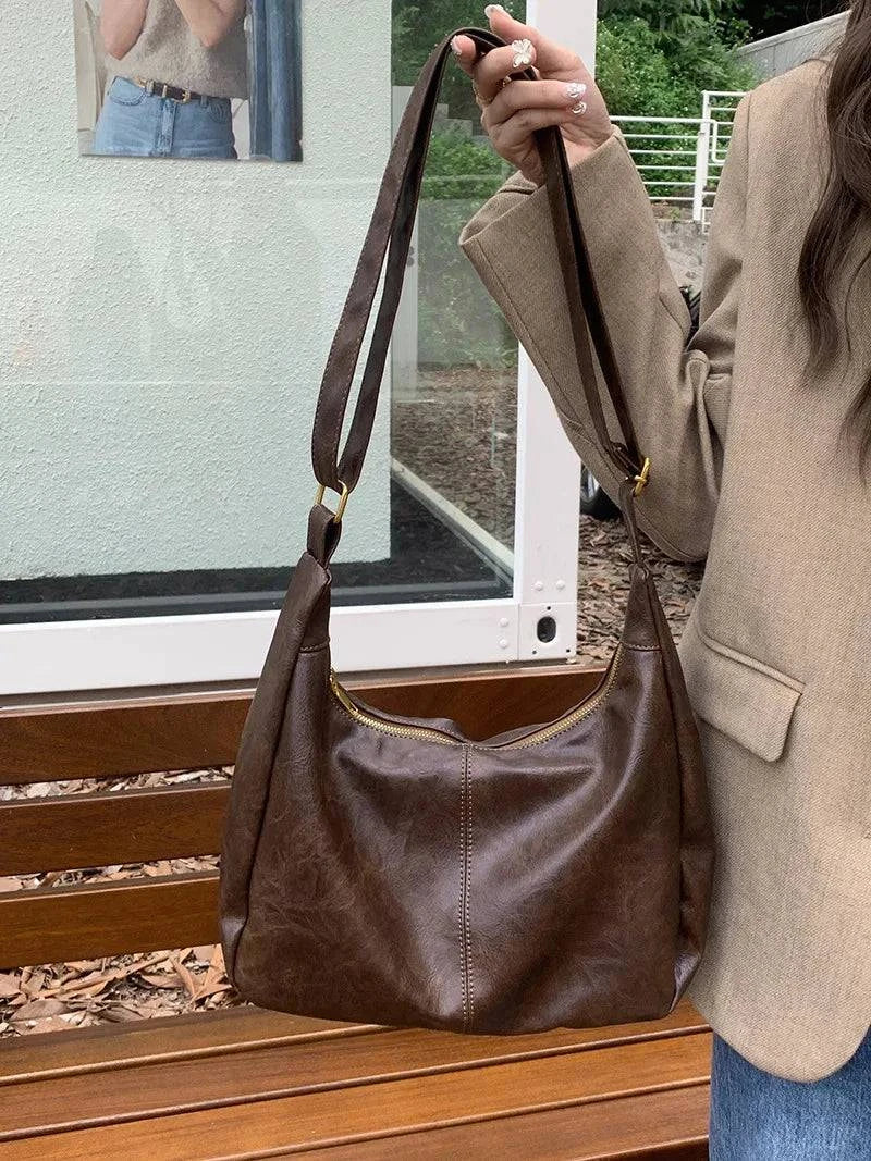 Alt text: Bolsa feminina de couro hobo marrom elegante e espaçosa.
