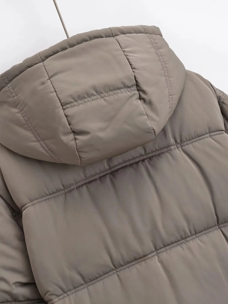 Um close-up da parte superior das costas e do capuz da Jaqueta Feminina Puffer para Inverno Zellum em marrom claro destaca a costura horizontal e a textura acolchoada e fosca contra um fundo liso e claro.
