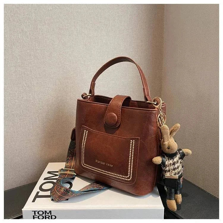 Alt text: Bolsa Tote Feminina Transversal Pequena Cristalle em couro marrom.