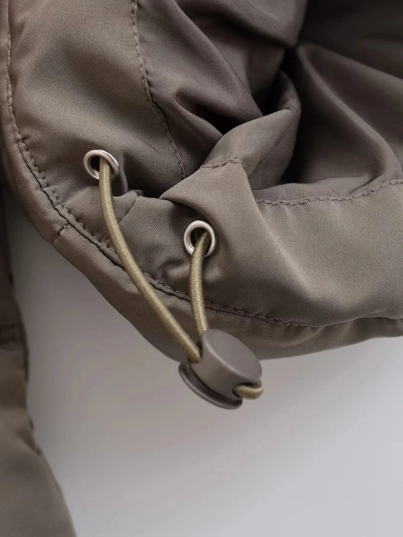 Close-up da Zellum Jaqueta Feminina Puffer para Inverno na cor cáqui, com cordão de ajuste com ilhós de metal e fecho de cordão redondo que permite ajustes fáceis. O tecido macio e levemente enrugado acrescenta conforto e estilo moderno.